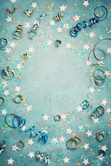 Party, carnival or birthday frame with colorful confetti and streamer on vintage blue table top view. Flat lay style. Holiday mockup. Greeting card with copy space.