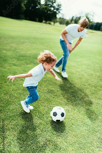 high angle view of cheerful father and son playing soccer in park