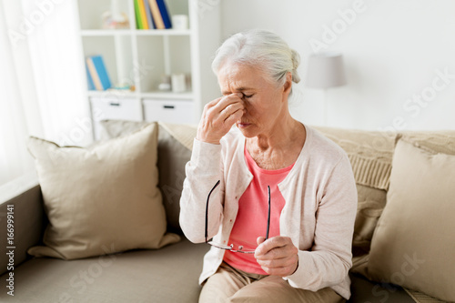 senior woman with glasses having headache at home