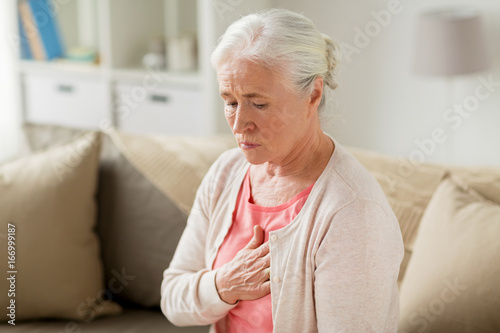senior woman suffering from heartache at home