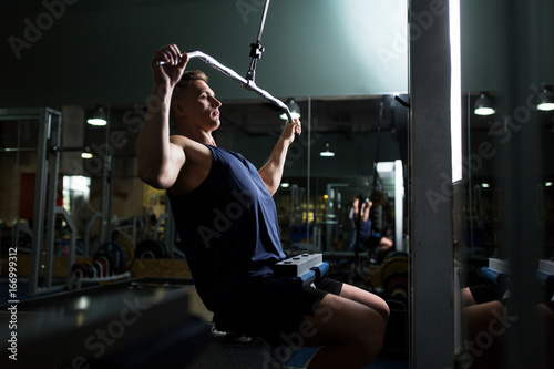 man flexing muscles on cable machine in gym