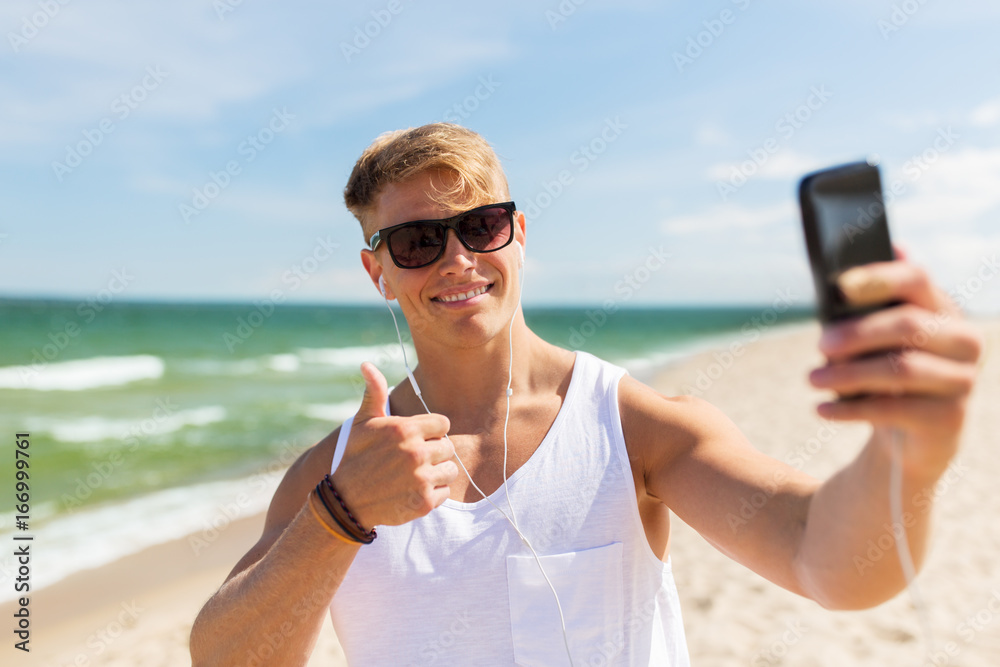 man with smartphone taking selfie on summer beach