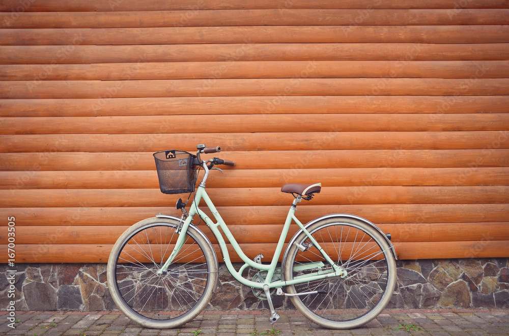 Close up of blue retro vintage bicycle with basket on wooden wall background. Urban lifestyle. Copy space.