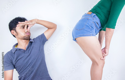 Young man covers him nose because of woman farting make a bad smell, Young man looking at her and covering him nose.