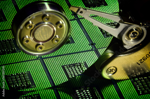 Open Hard Disk Drive with reflection of aligned CPU Processors and green light effetcs. background photo