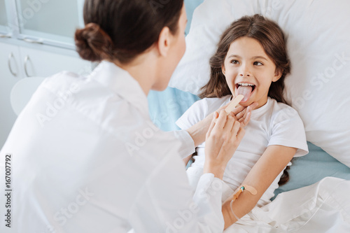 Pleasant cheerful girl being examined by a doctor