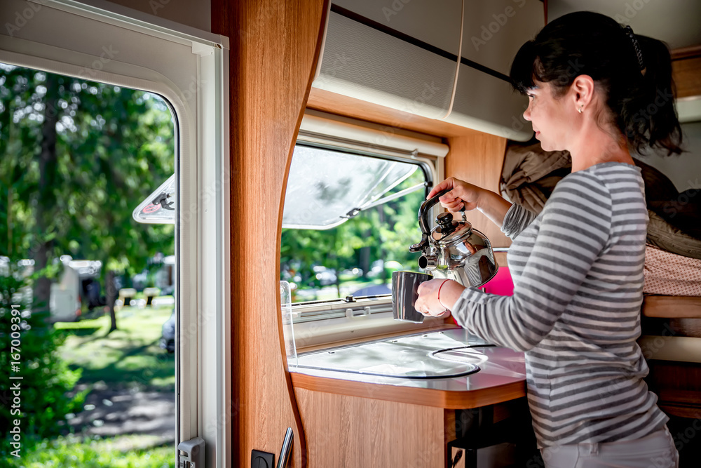 Fototapeta premium Woman cooking in camper, motorhome interior