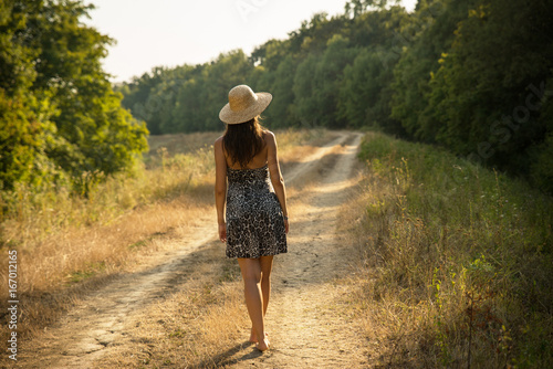 Girl walking on a countryside rural road in the middle of nature in summer © icephotography