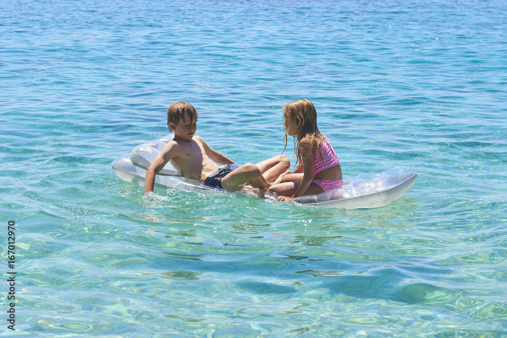 Happy Sister and Brother Children Playing with Inflatable Mattress at Adriatic Blue Sea, Hvar island, Croatia. Concept of happy summer holiday Happy Sister and Brother Children Playing with Inflatable Mattress at Adriatic Blue Sea, Hvar island, Croatia. Concept of happy summer holiday