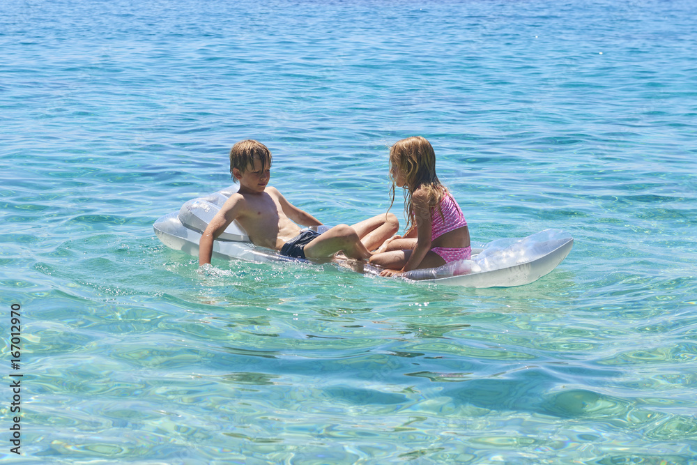 Happy Sister and Brother Children Playing with Inflatable Mattress at Adriatic Blue Sea, Hvar island, Croatia. Concept of happy summer holiday