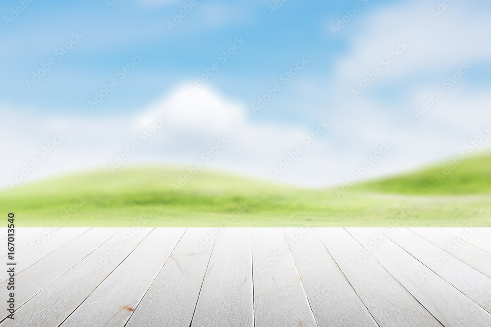 Wood table top on blurred mound slope green grass natural background in morning time.