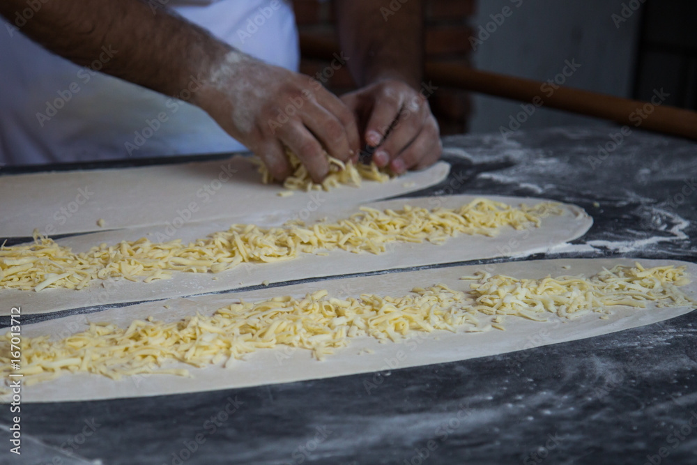 Men's hands prepare pizza dough on a marble table