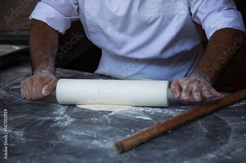Men's hands prepare pizza dough on a marble table