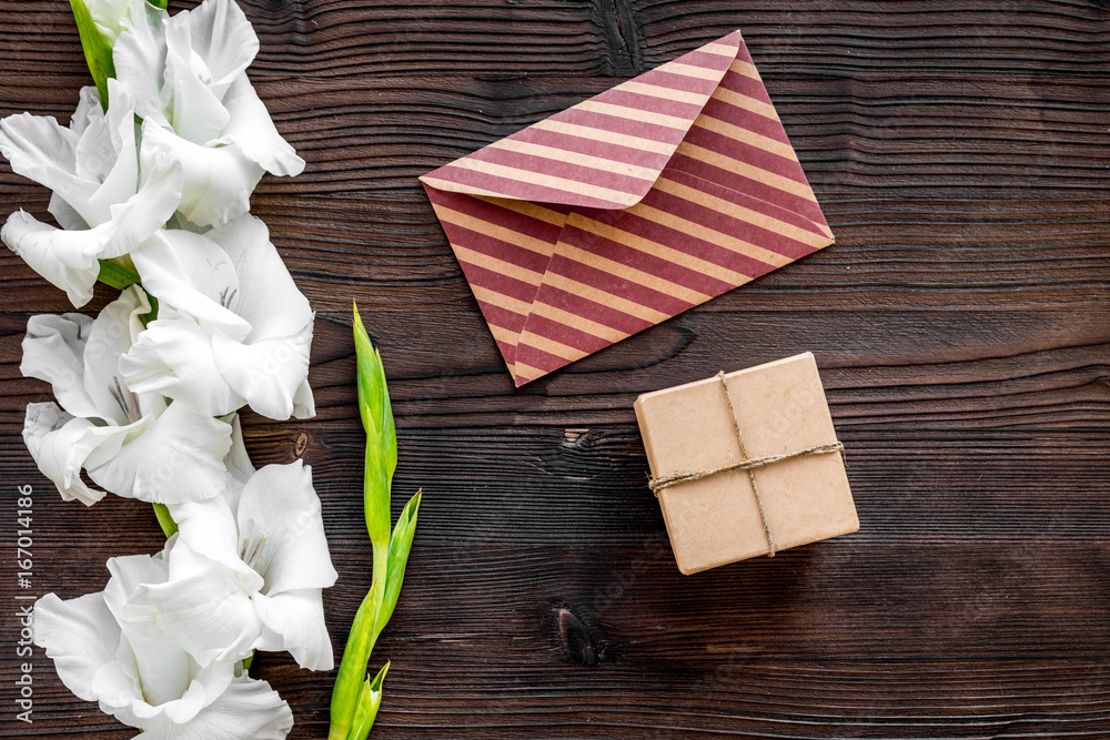 Congratulation. Envelope and box in kraft paper near flower gladiolus on wooden table top view copyspace Congratulation. Envelope and box in kraft paper near flower gladiolus on wooden table top view copyspace