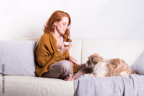 schöne, rothaarige Frau mit oranger Strickjacke erzieht ihren Hund