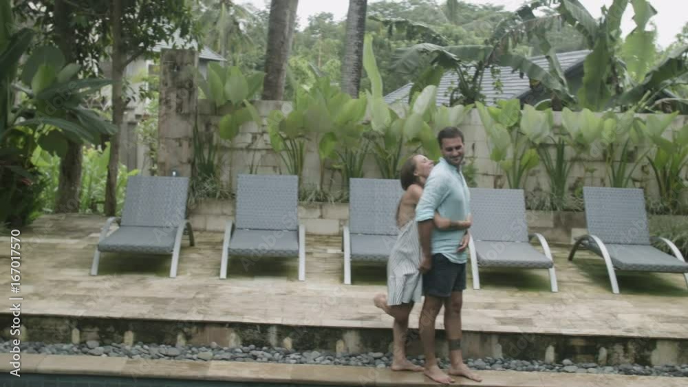 Happy couple standing on the edge of the pool outside Happy couple standing on the edge of the pool outside