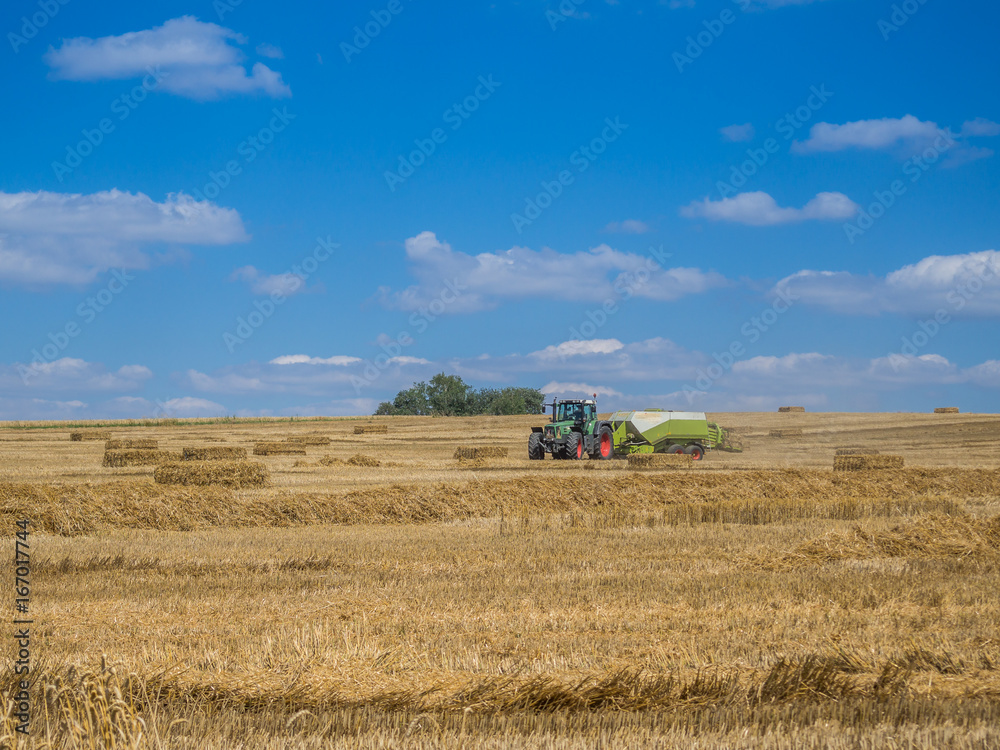 Fototapeta premium Traktor bei der Strohernte