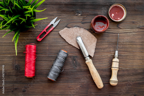 Leather craft workshop. Tools on dark wooden table background top view