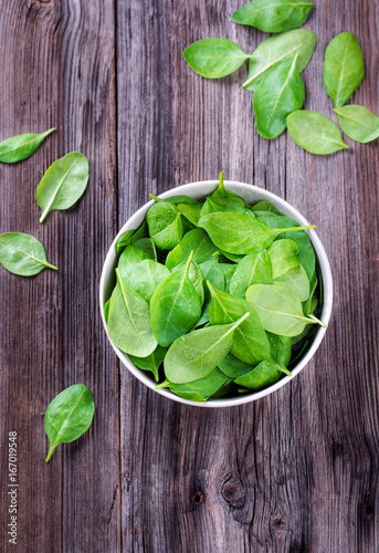 Fresh spinach leafs with drops in a bowl on a rustic wooden table