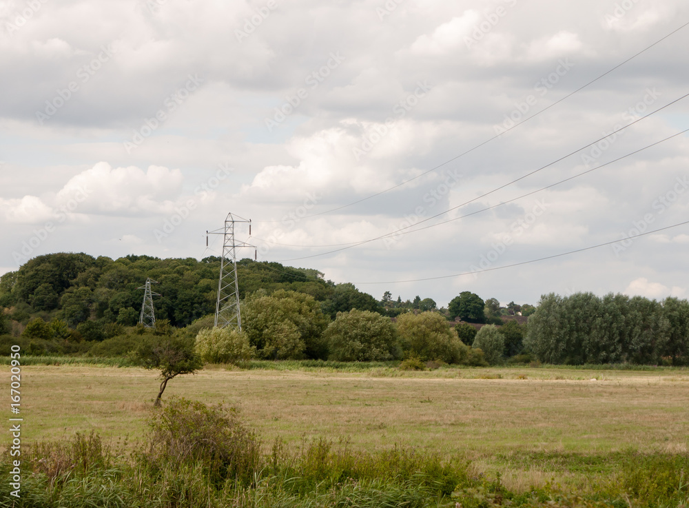 a metal pylon outside in the country with wires overhead