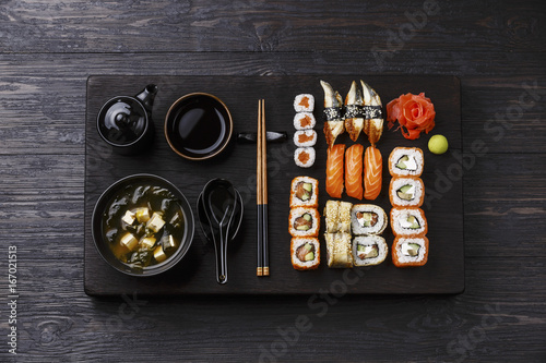 Sushi Set nigiri and sushi rolls and Miso Soup with tofu on wooden serving board block on black background