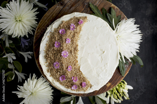 Marzipan Almond Cake with a Orange Blossom Mascarpone Frosting on a wooden pedestal, served with Rosé wine.  Photographed on a black/gray background.