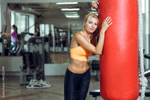 Tired young woman training with punching bag after training at gym © producer