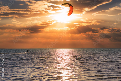 Kitesurfers ride on the waves at sunset