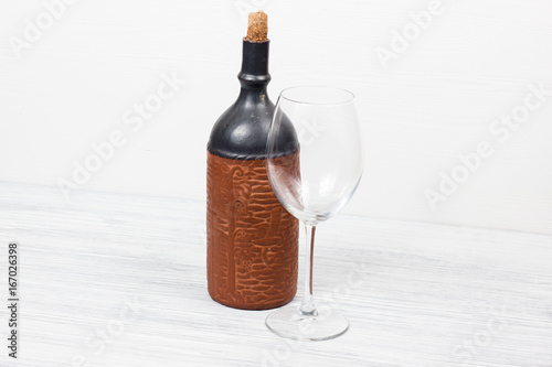 Black bottle of wine and wneglass on the wooden background photo