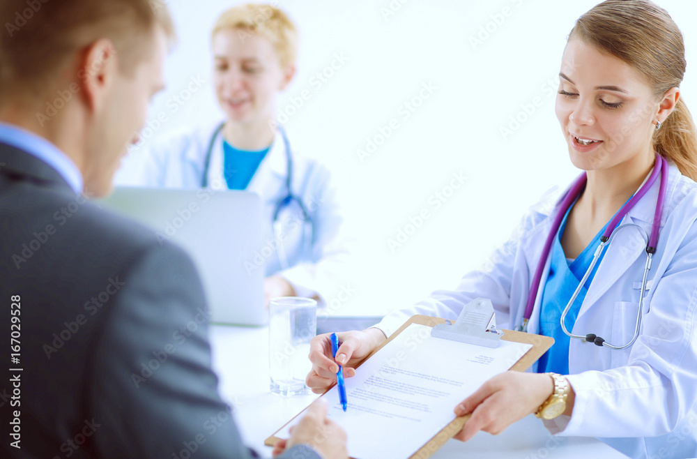Obraz premium Beautiful young smiling female doctor sitting at the desk