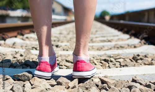 Girl walking on rail road track in red speakers