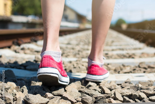 Girl walking on rail road track in red speakers