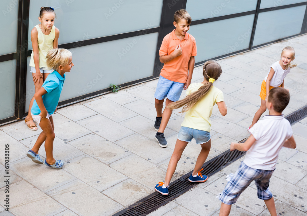 kids actively playing and running together on street on summer day