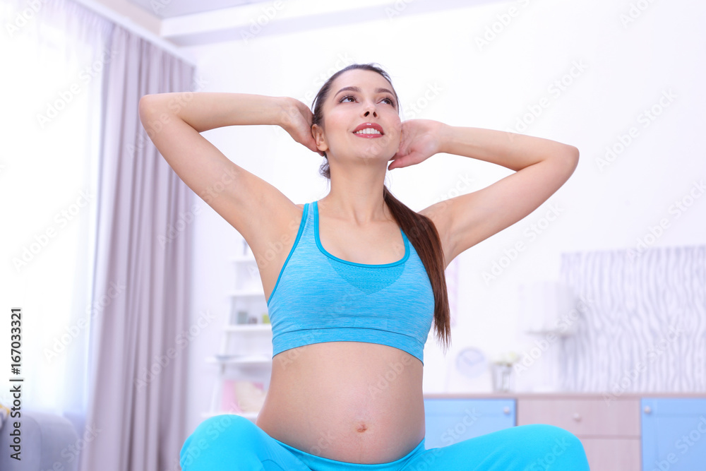 Young pregnant woman training at home. Health concept