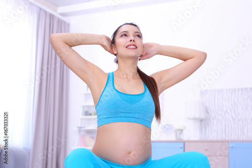 Young pregnant woman training at home. Health concept