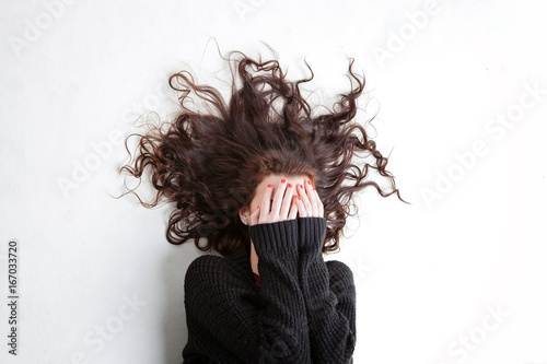 Foto Dark haired female covering her face with her hands with her hair out around her