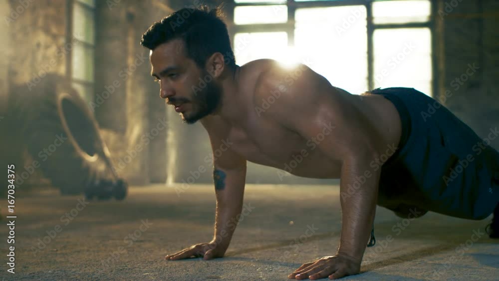 Muscular Shirtless Man Puts Heavy Effort into Doing Push-ups in a Deserted Factory Remodeled into Gym. Part of His Cross Fitness Workout/ High-Intensity Interval Training. 