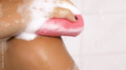 Happy woman washing herself with sponge and soap in shower slow motion closeup