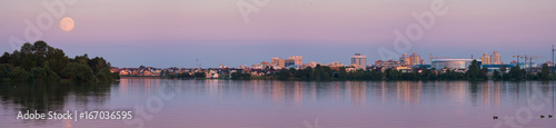 Moon perigee, Belarus. Panoramic View Of Minsk City with fullmoon and picturesque town with colorful buildings Around the coastal zone. Perigee full moon over the skyscrapers of Minsk, Belarus.  © Vlad Sokolovsky