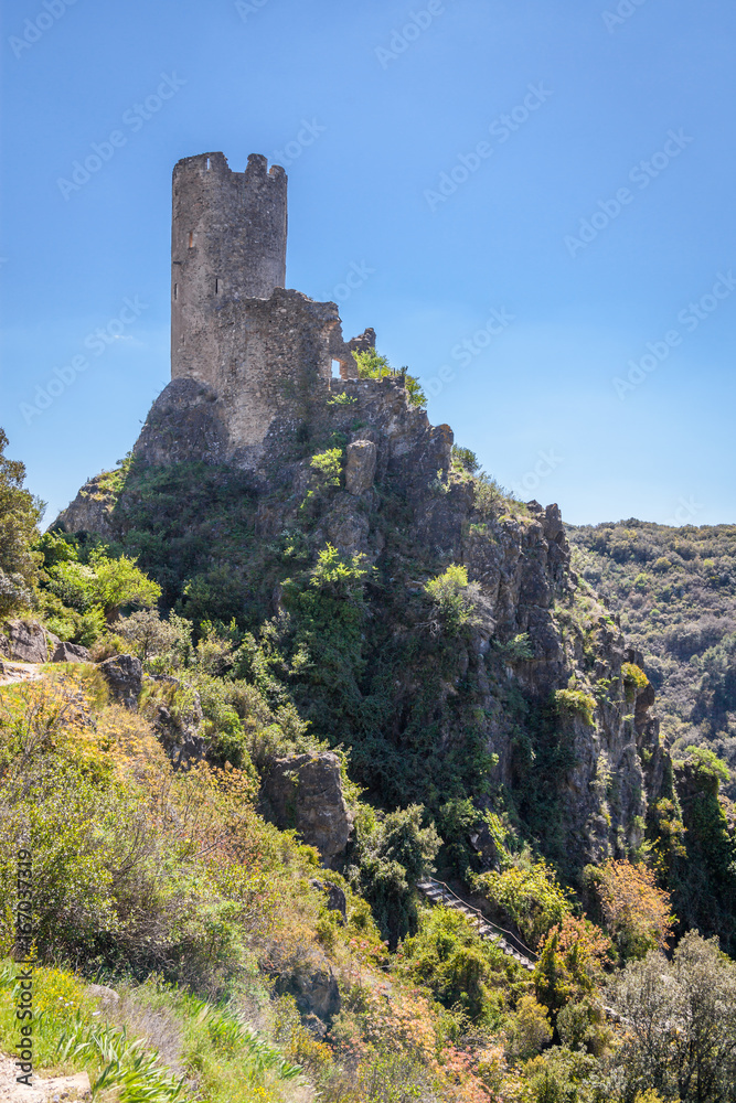 ruins of Lastrous castle in France on top of the mountain on a sunny day with trees