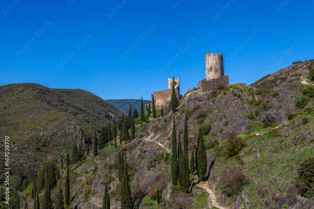Lastrous castle in France on top of the mountain on a sunny day with trees and path