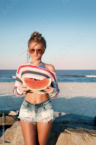 Happy woman eating watermelon on the beach.