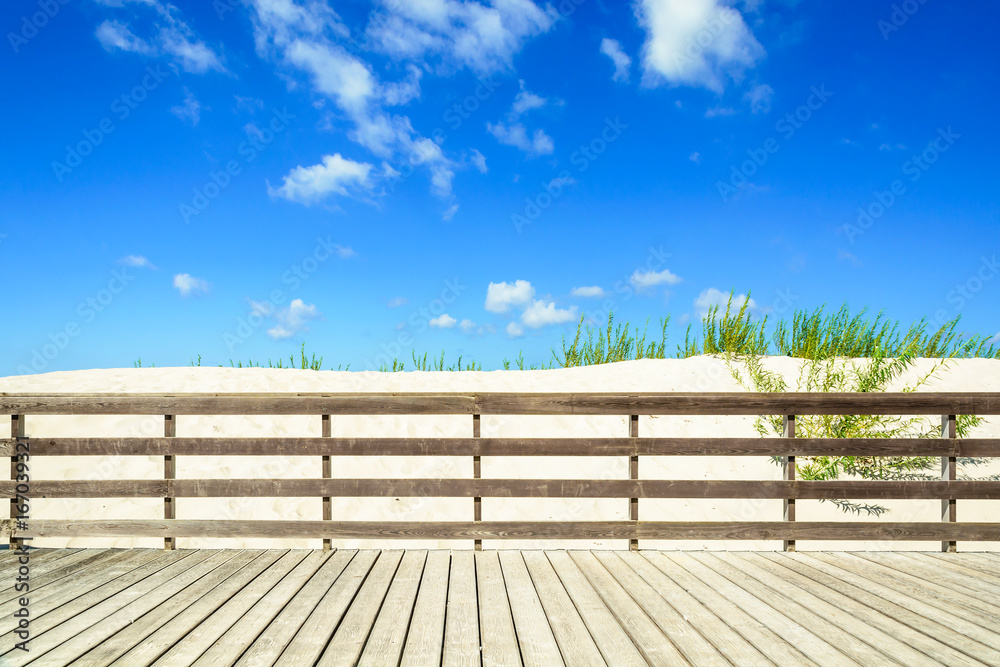 Sandy beach on sunny summer day with wooden walkway