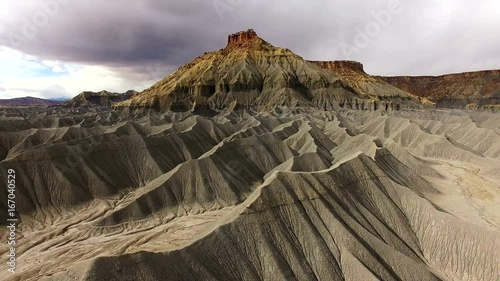 Flying over desert terrain showing sandy hills at the base of a mesa in the Utah badlands.
