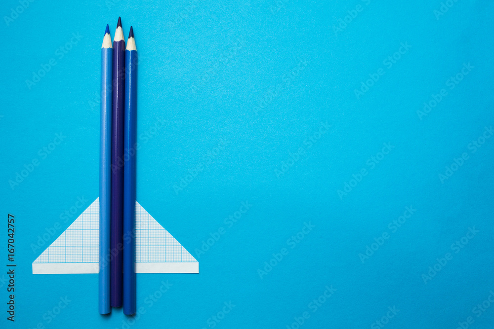 Airplane made of pencils and paper on a blue background. Space for text. Airplane made of pencils and paper on a blue background. Space for text.