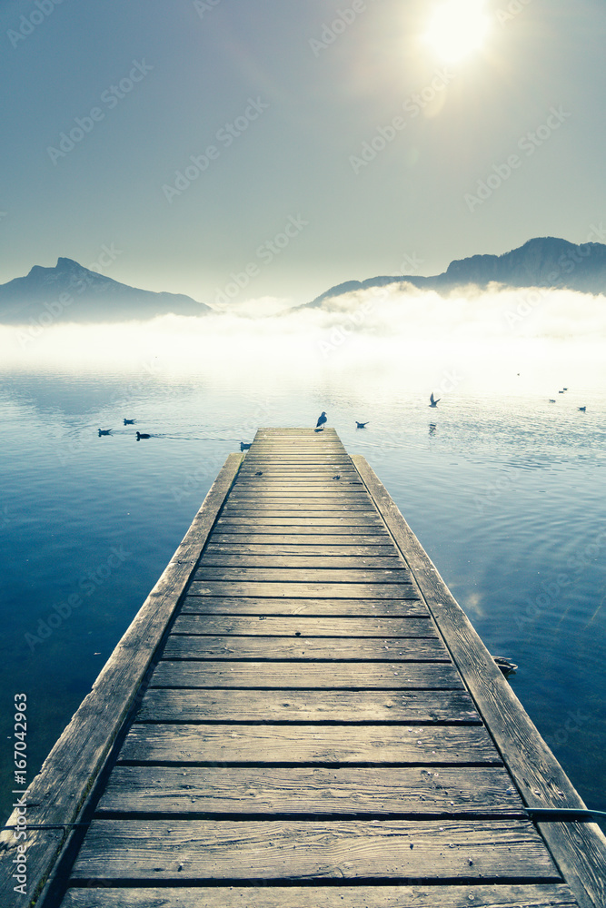 View on Pier with seagulls by mountain lake Mondsee in Autria