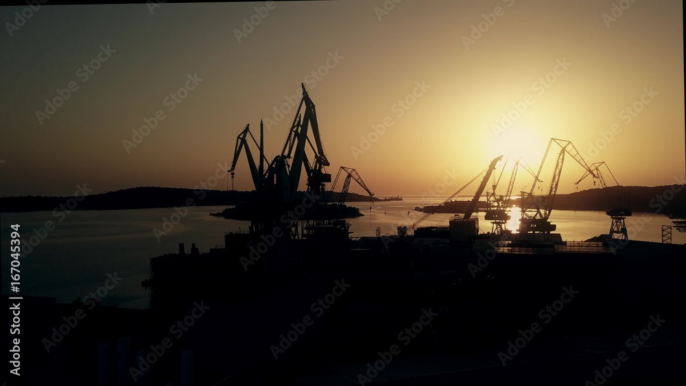 Aerial view of the shipyard cranes and the sea harbour at sunset