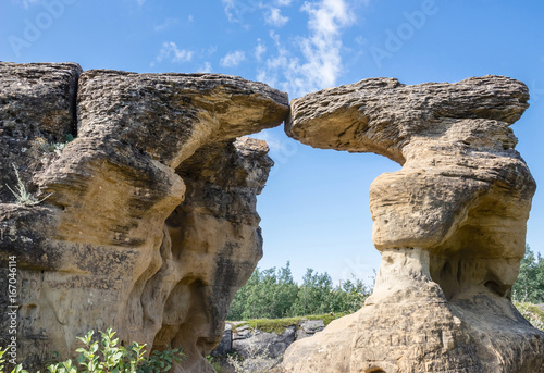 horizontal image of two beautiful majestic tall and naturally carved sandstone formations touching together at the very top under a blue sky in the summer. © nat2851terry