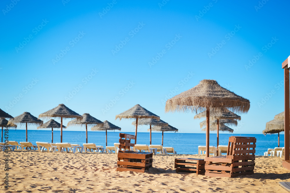 Sunny sky and chairs with parasol on the beautiful beach of Portugal
