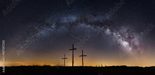 the milkyway galaxy arching over three crosses